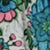 Close-up of fabric with a floral pattern featuring blue, pink, and green flowers and leaves in a soft, delicate print.