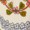 A close-up of a decorative pattern featuring green and brown leaves, red dots, and a row of light grey circular shapes enhanced with botanical details.