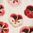 A close-up of patterned fabric featuring red and pink pansy-like floral designs with a delicate, textured look.