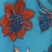 A close-up of a fabric with a blue background and a red and dark blue floral pattern.