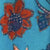 A close-up of a fabric with a blue background and a red and dark blue floral pattern.