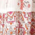 A close-up of fabric featuring an intricate floral and geometric print in shades of red, orange, and gray.