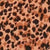 Close-up of a leopard print pattern with irregular black spots on a tan and light brown background.