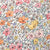 A close-up of fabric with a dense floral pattern featuring pink, yellow, orange, and purple flowers with green leaves in vibrant detail.