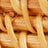 Close-up view of light brown woven rattan strands, showcasing a detailed, interlaced texture.