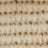 A close-up, blurry view of a beige woven textile with a visible horizontal and vertical grid pattern.