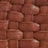 Close-up view of a woven texture pattern, featuring interlaced, rectangular strips in a reddish-brown color.