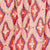 Close-up of fabric featuring a repeating geometric pattern in red, orange, and blue diamond shapes, creating a vibrant and bold design.