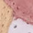 Close-up of a dessert featuring beige, pink, and white layers with a creamy texture and small holes, highlighting its rich visual appeal.