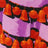 Close-up of a pattern featuring orange bells and round shapes on dark garlands, creating a vibrant purple scene.