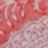 A close-up, blurred image of a patterned surface in shades of red and pink, featuring lace-like white detailing.