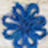 A blurred image of a blue, flower-shaped object with multiple rounded petals softly bathed in light.
