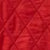 Close-up of red quilted fabric featuring a striking diamond pattern and textured stitching.
