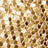 Close-up view of a gold sequined surface, showing tightly arranged shiny circular sequins reflecting light.