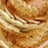 Close-up of a round challah loaf with a golden-brown crust and an intricate braided design on top.