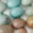 A blurred close-up of several pastel-colored, oval-shaped objects—light blue, green, and beige—arranged softly together.