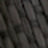 A close-up, blurry image showing a pattern of rectangular, dark gray bricks or tiles arranged in diagonal rows.
