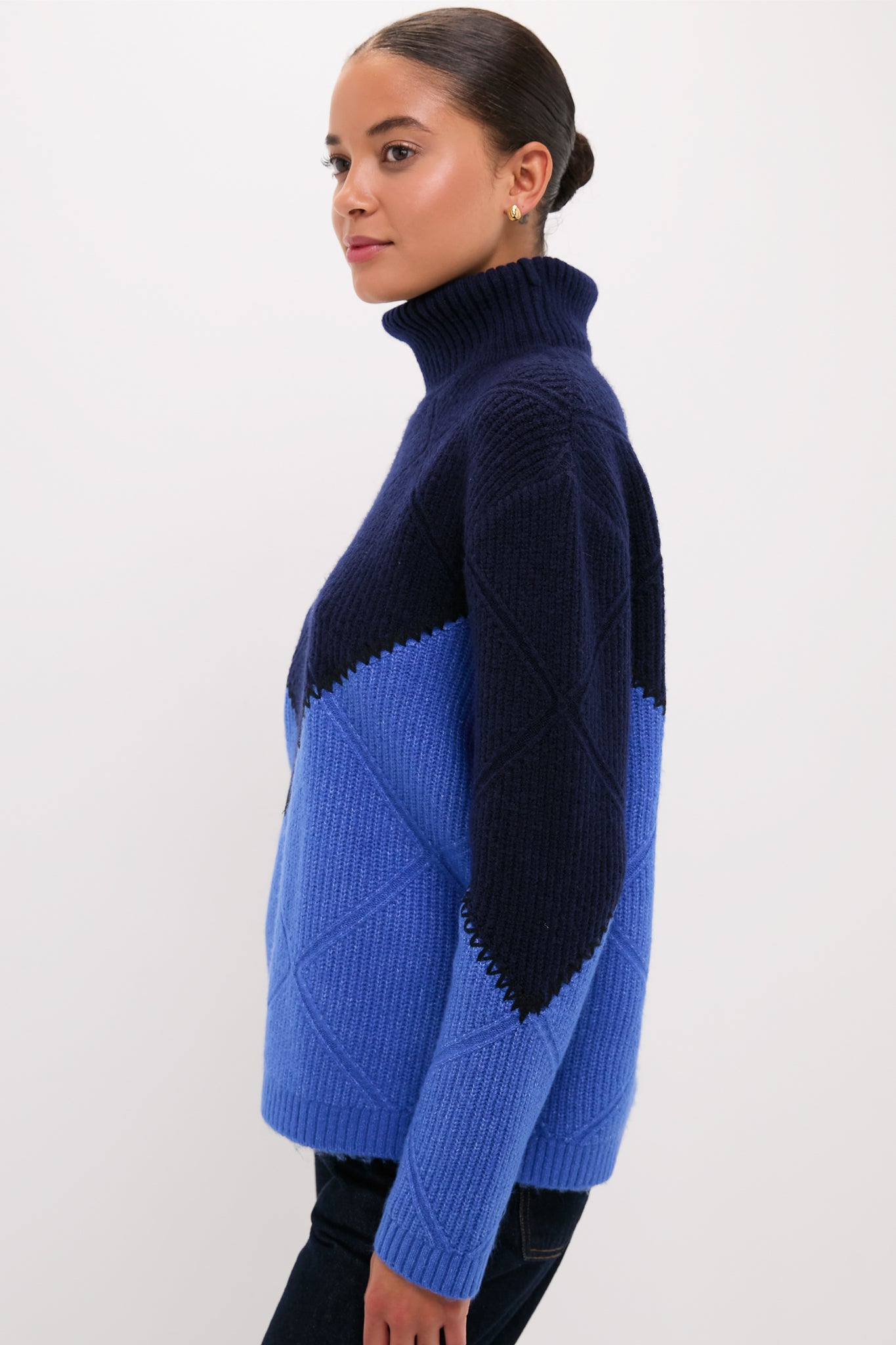 Young woman in profile wearing the Navy & Cerulean Diamond Demi Turtleneck, showcasing its classic, effortless design with a fun, high-end diamond-quilted pattern.