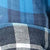 Close-up of blue and black plaid flannel fabric with white accents, displaying a pattern of intersecting lines and squares.
