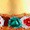 Close-up of a festive cake topped with colorful candied fruit pieces, including green and red varieties, displayed on a golden surface.
