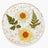 A round plate featuring two pressed yellow-orange flowers and two green fern leaves embedded in a clear resin with scattered gold flecks.
