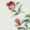 Two vibrant red and yellow roses with lush green leaves rest gracefully on a soft, light surface.