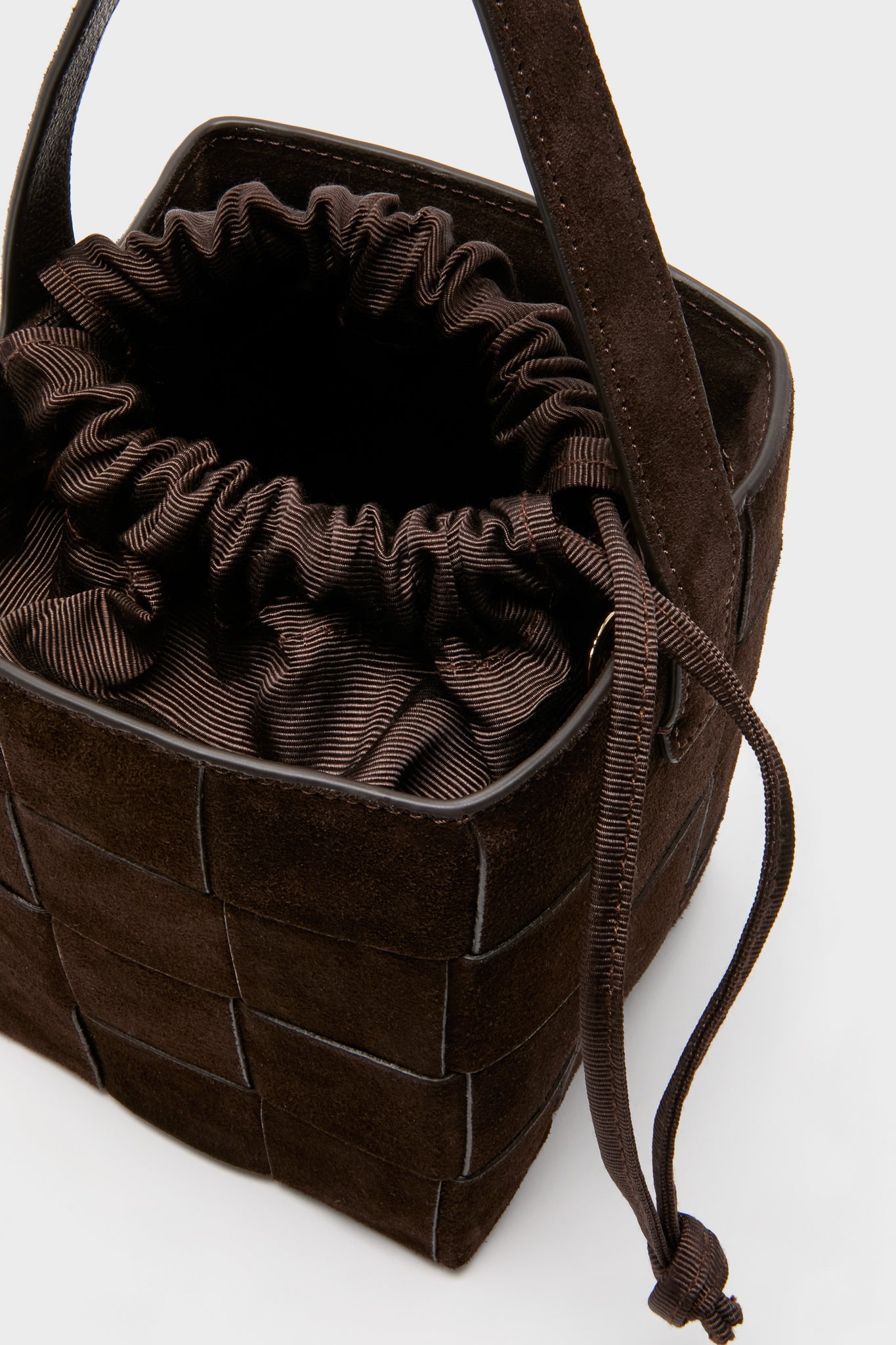 Woven Tmoro Suede Laith Top Handle Bag in a classic, effortless design with a dark brown suede weave, top handle, and fun drawstring closure for a high-end look.