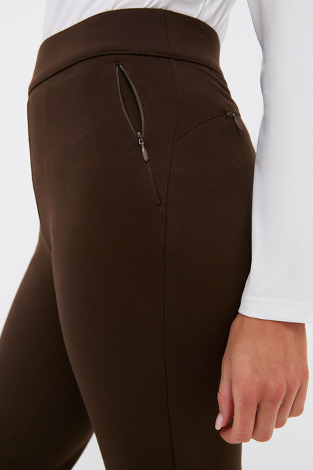 Side view of a classic, high-end Petite Chocolate Brown Compression September Pant with effortless style, featuring a high waistband and zippered pockets, worn with a white top.