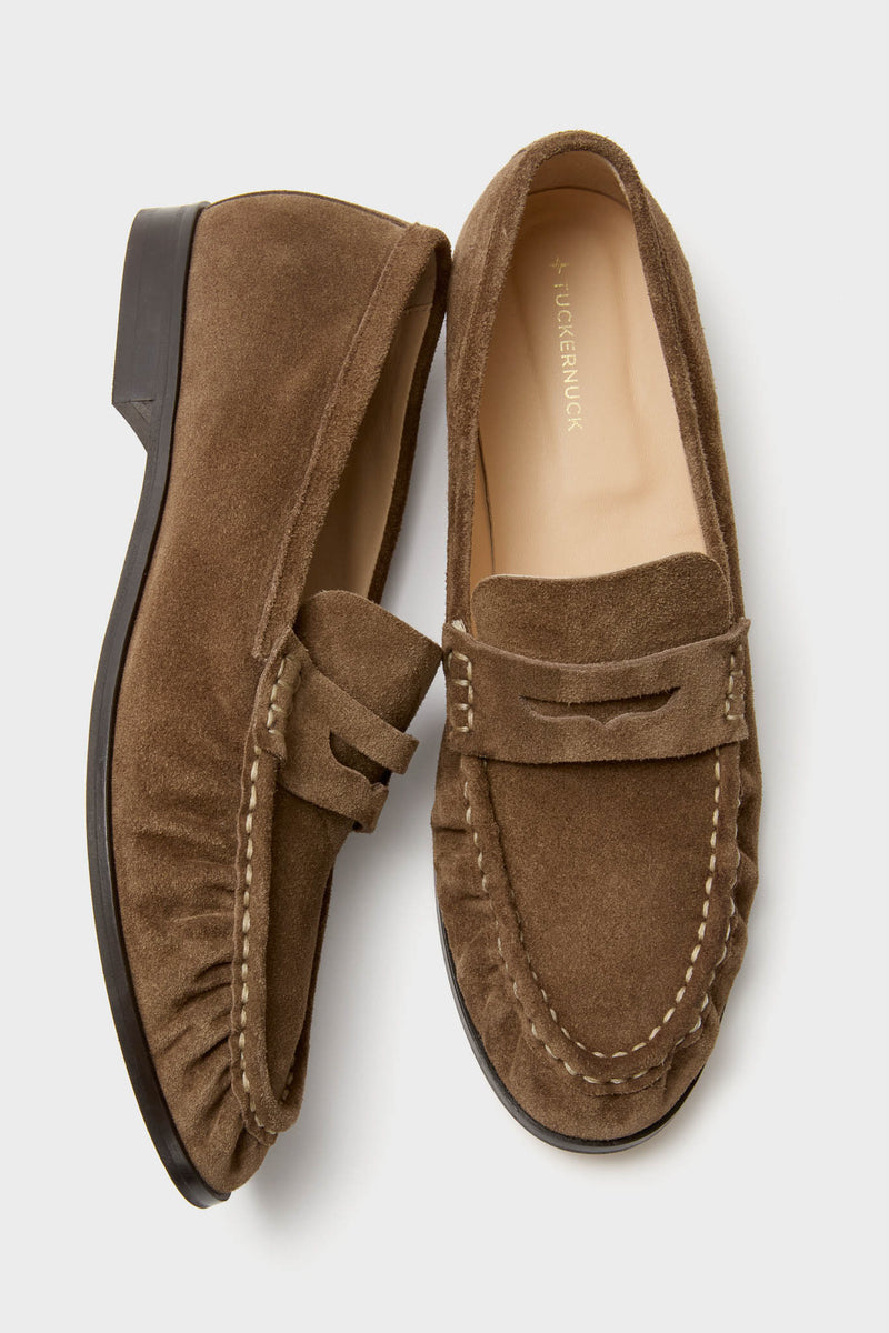A pair of brown suede loafers with contrast stitching and black soles.