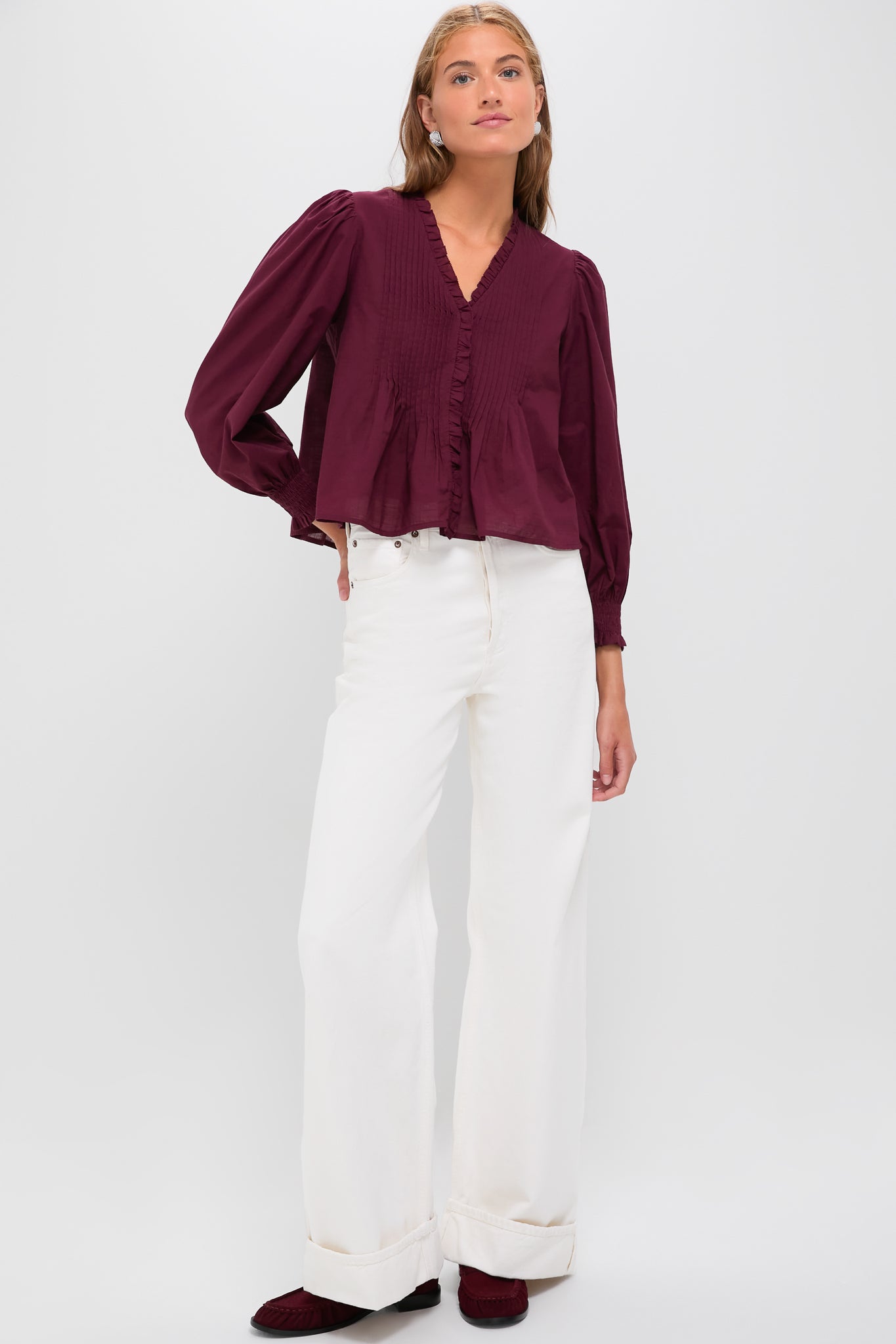 A classic, effortless look featuring the Exclusive Burgundy Anise Long Sleeve Top with pintuck detailing, paired with high-waisted white jeans and burgundy loafers for a fun, high-end style.