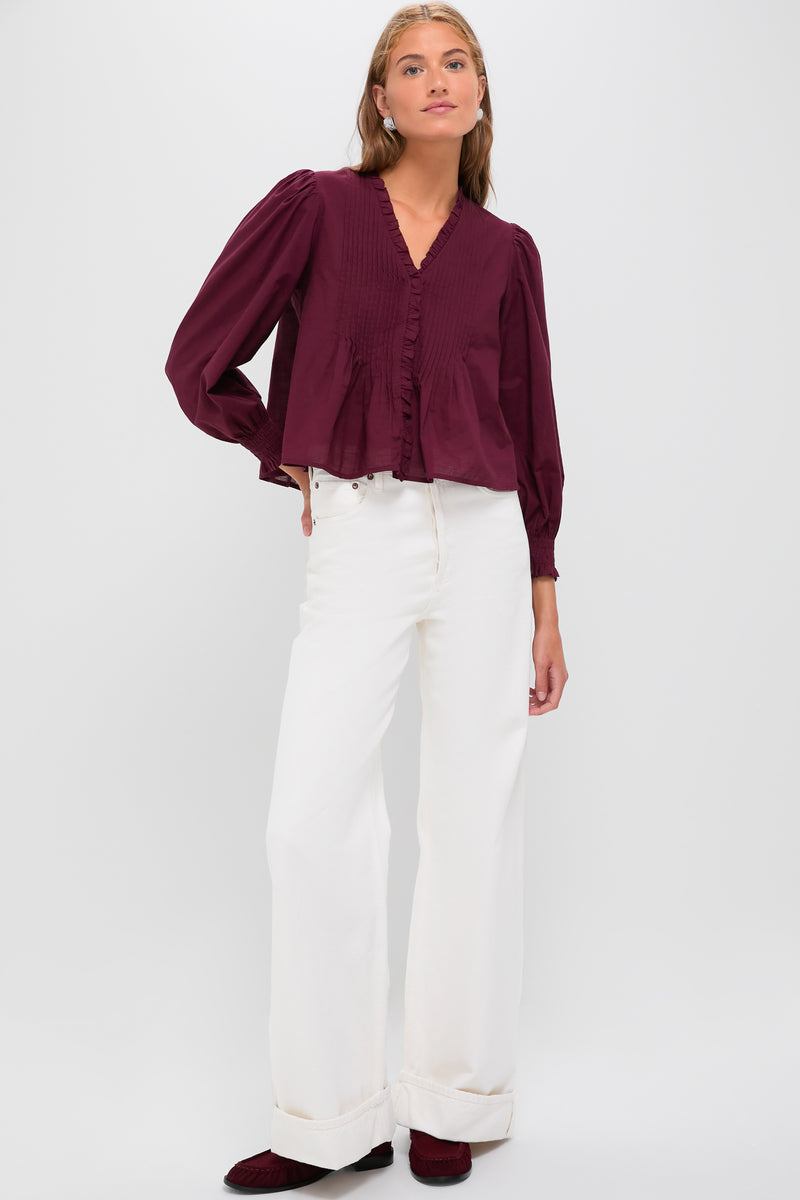 A classic, effortless look featuring the Exclusive Burgundy Anise Long Sleeve Top with pintuck detailing, paired with high-waisted white jeans and burgundy loafers for a fun, high-end style.