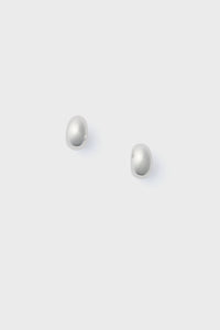 A pair of small, round, white pearl stud earrings by Lie Studio is displayed on a simple light grey background.