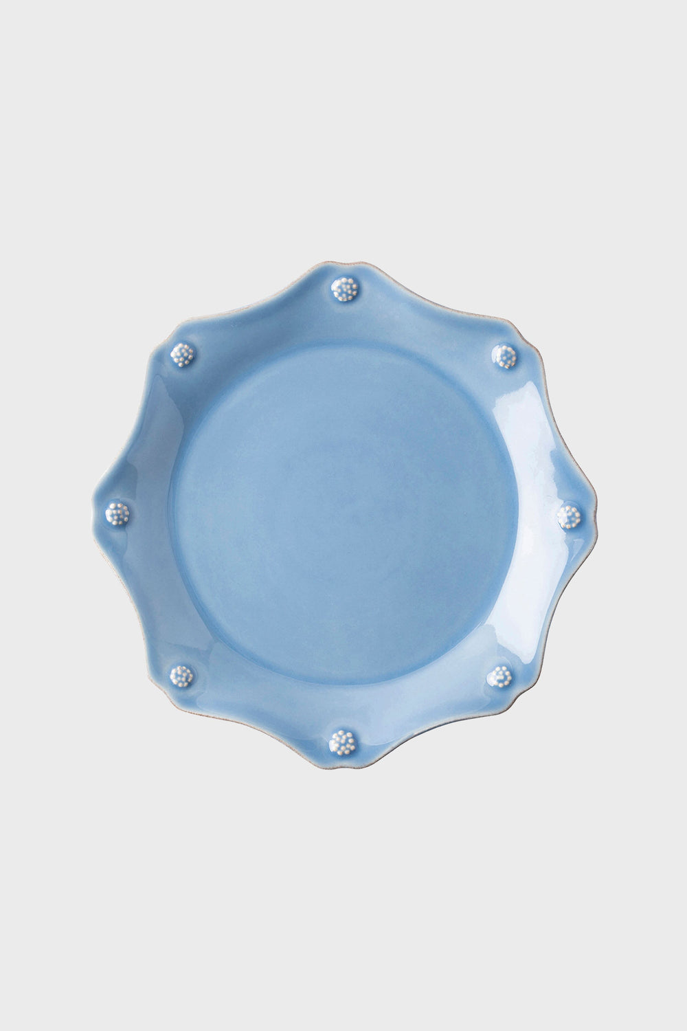 A round, light blue ceramic salad plate with a scalloped edge and small flower details on the rim from Juliska's Berry & Thread Collection.