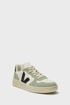 A VEJA sneaker in white and light green with a perforated toe, beige laces, black V logo on the side, and a beige recycled-material sole, displayed against a plain white background.