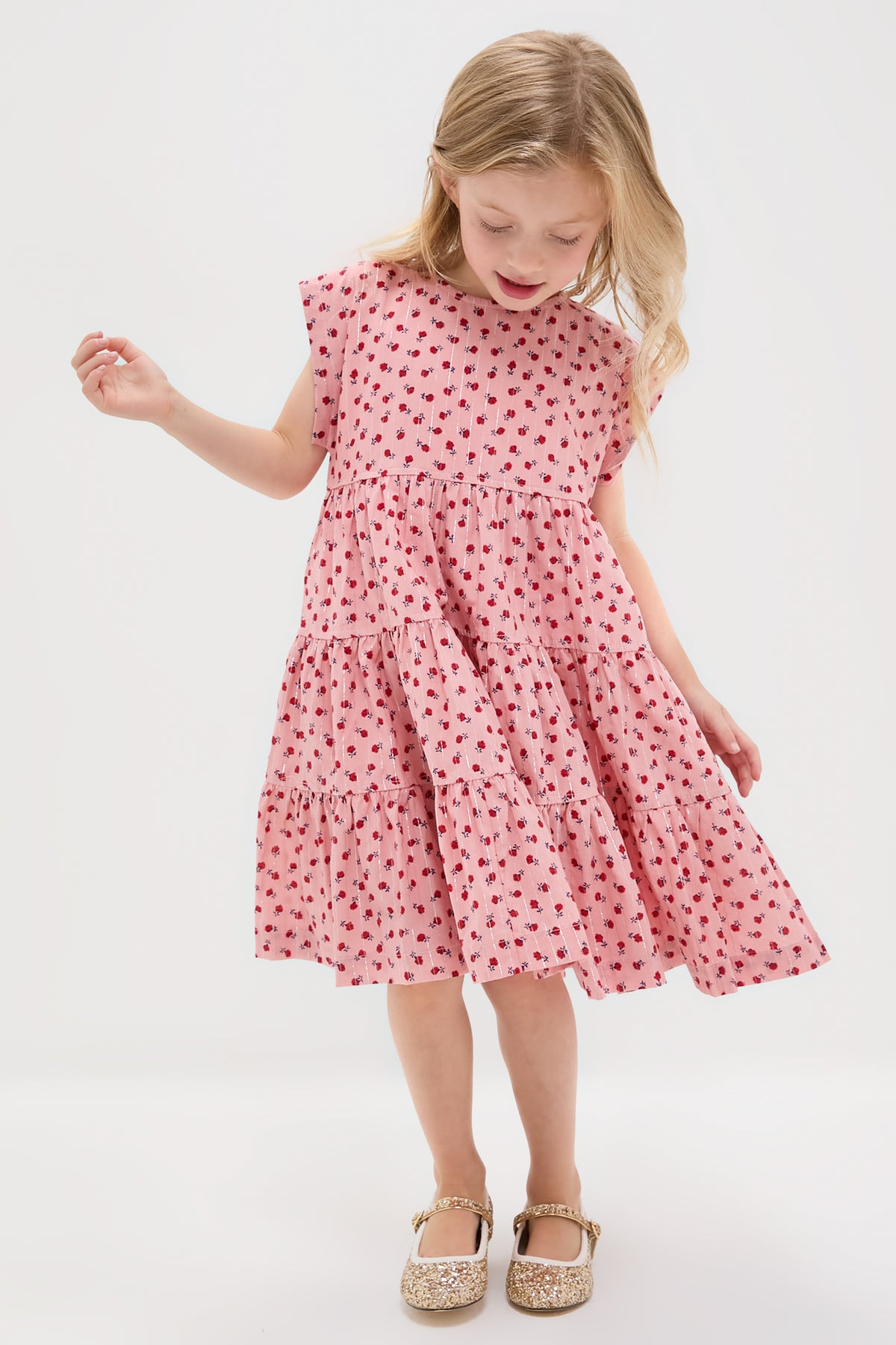 Young girl in classic Girls Peachy Dress, an effortless, high-end tiered outfit with floral pattern and sparkly shoes, embodying fun and confidence.