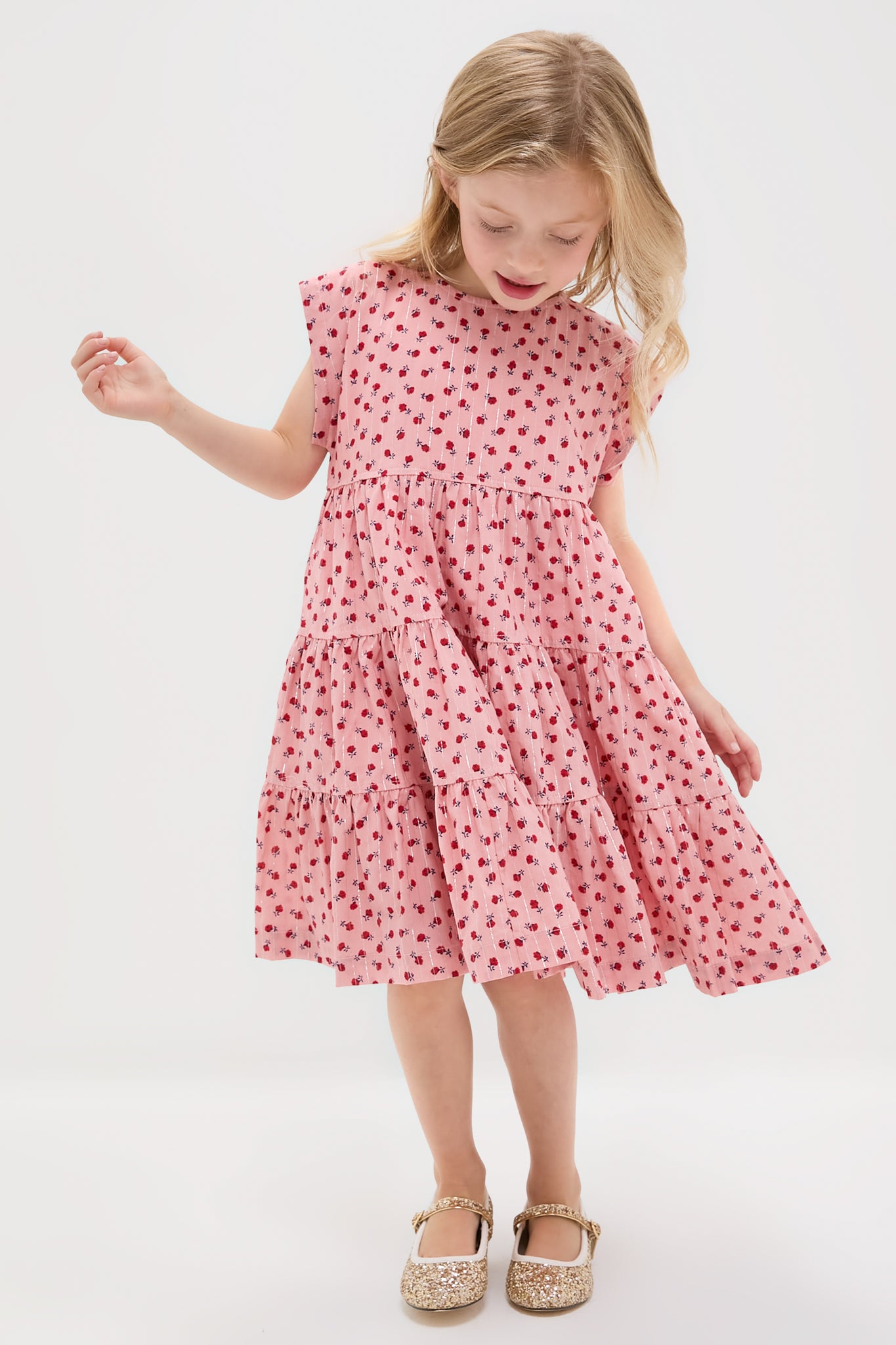 Young girl in classic Girls Peachy Dress, an effortless, high-end tiered outfit with floral pattern and sparkly shoes, embodying fun and confidence.