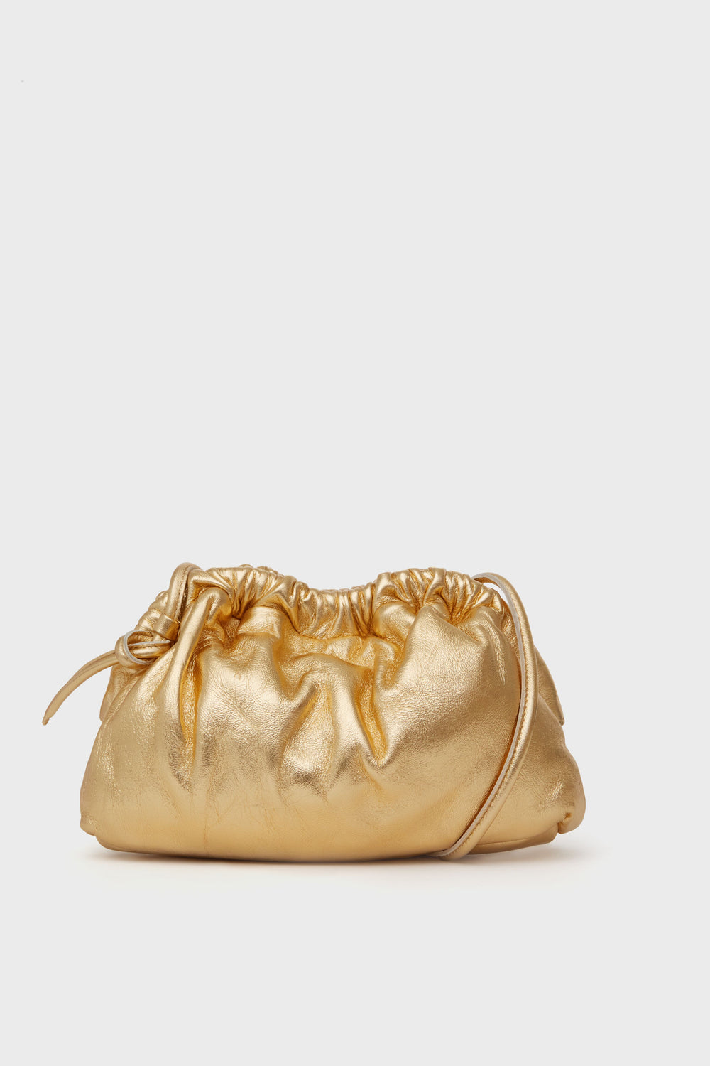 The Mansur Gavriel Gold Mini Cloud Clutch, crafted from Italian lambskin leather, features a gathered ruched design and a slim strap, making it the perfect chic crossbody bag.