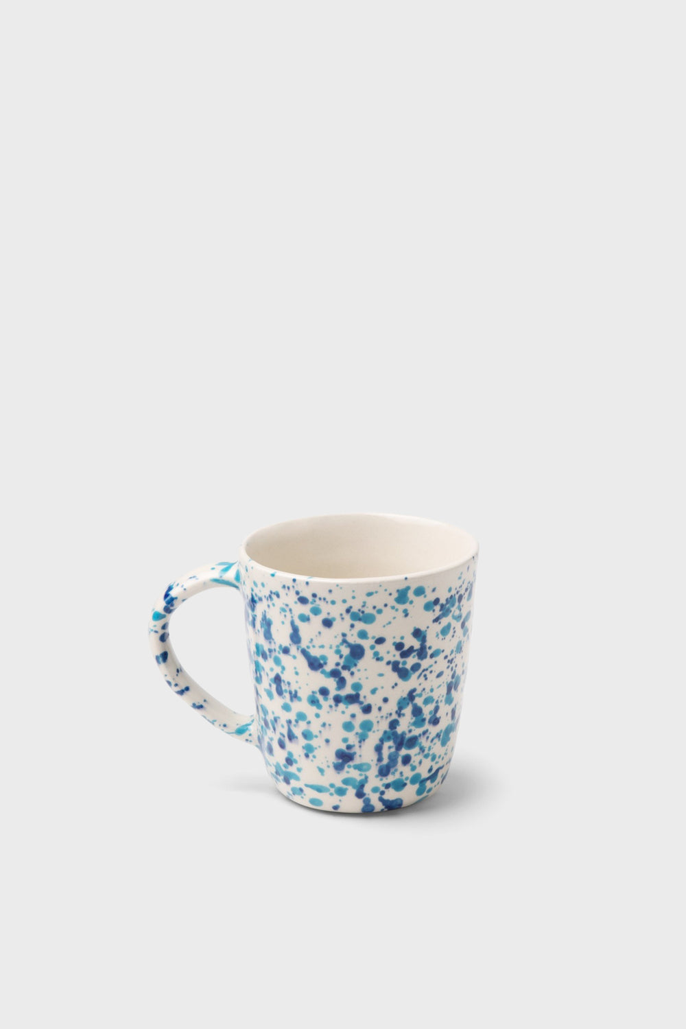 The Blue Pheasant white ceramic mug features a blue speckled pattern inspired by classic spongeware, adding charm to any handmade dinnerware collection.