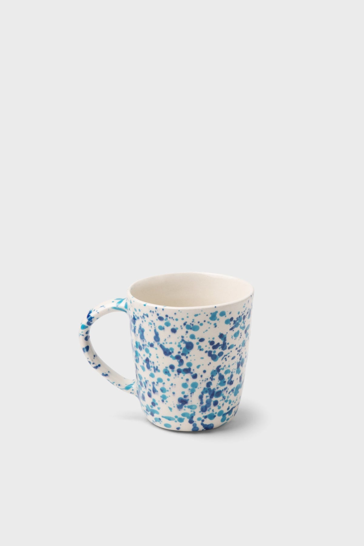 The Blue Pheasant white ceramic mug features a blue speckled pattern inspired by classic spongeware, adding charm to any handmade dinnerware collection.