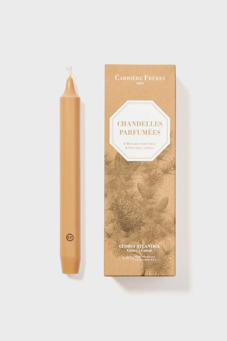 A beige scented taper candle sits next to a Carrière Frères luxury box labeled Chandelles Parfumées Cedrus Atlantica.