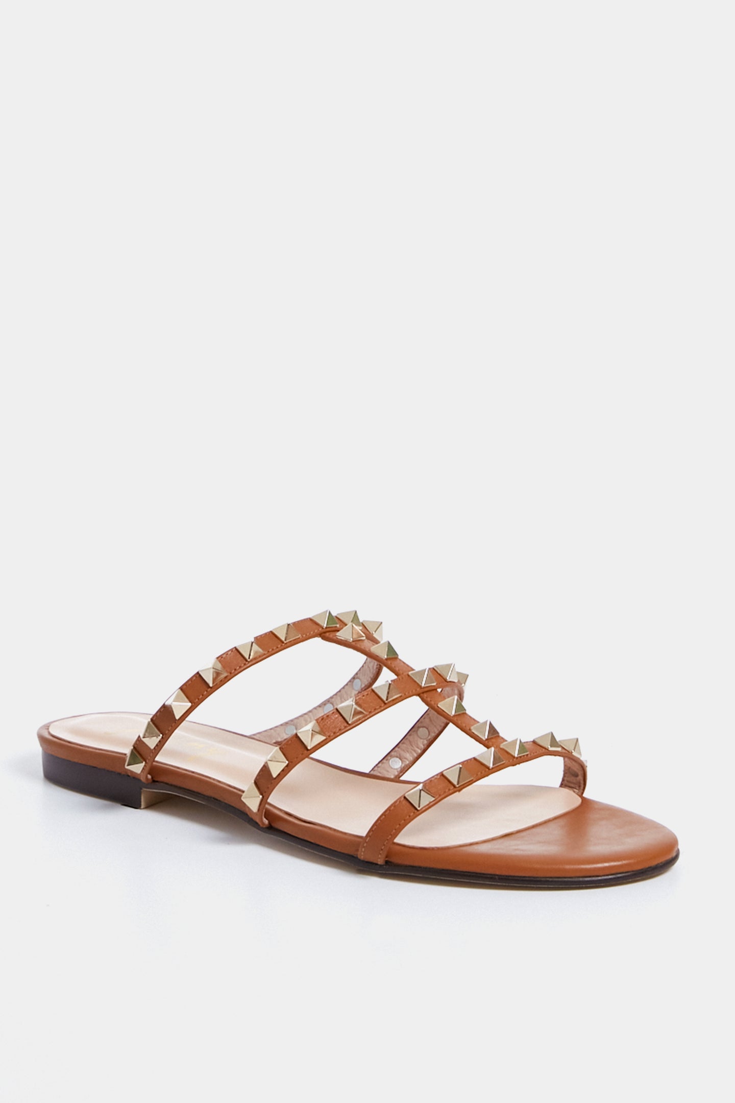 French Sole’s brown leather sandal features a low heel and four thin, gold-studded straps in a chic caged design, offering stylish comfort.