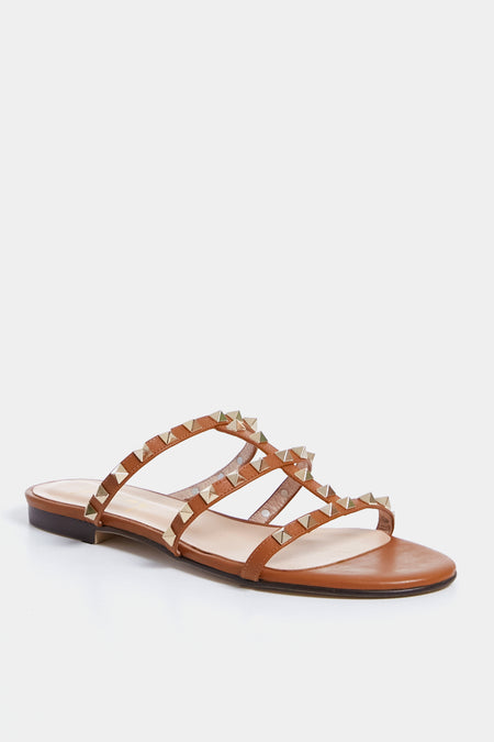 French Sole’s brown leather sandal features a low heel and four thin, gold-studded straps in a chic caged design, offering stylish comfort.