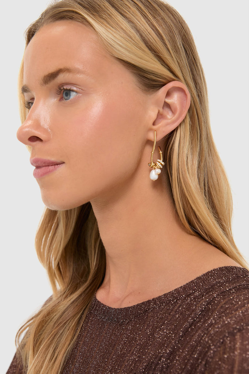 Young woman wears Pearl and Gold Charm Giselle Earrings: classic gold hoops with playful floral charms and a pearl drop, exuding an effortless, high-end, and fun elegance.