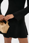 Classic Black Asra Mini Dress with ribbed texture, flared cuffs, and flared skirt, paired with a high-end beige-gold handbag for an effortless, fun look.
