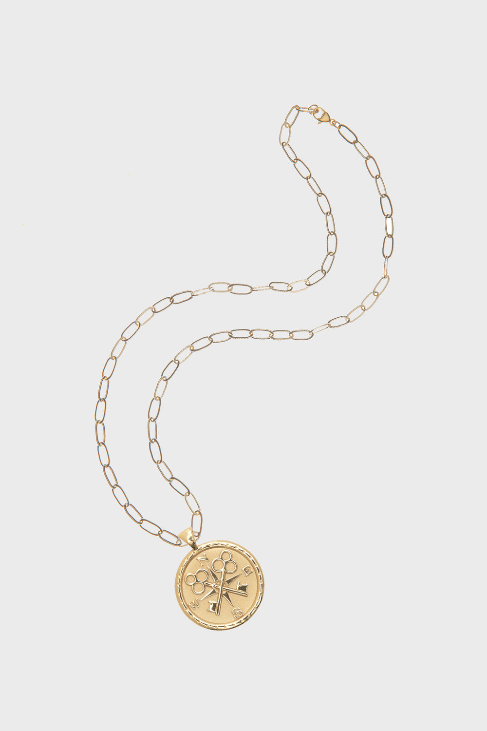 Jane Win Gold Forever Original Pendant: a 14k gold plated necklace with a round pendant featuring engraved flower, sword, and key motifs, inspired by classic compass coin designs.