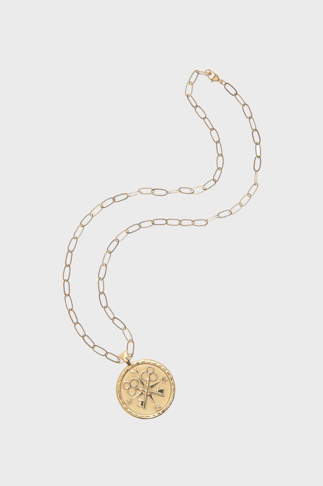 Jane Win Gold Forever Original Pendant: a 14k gold plated necklace with a round pendant featuring engraved flower, sword, and key motifs, inspired by classic compass coin designs.