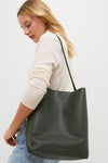 Woman in a light sweater and jeans carrying the classic Seaweed Everyday Cabas tote, a high-end, effortless, fun accessory with a magnetic closure and Italian pebbled leather.