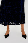 A person wearing a Hyacinth House navy floral dress and black pointed-toe heels stands against a light background.
