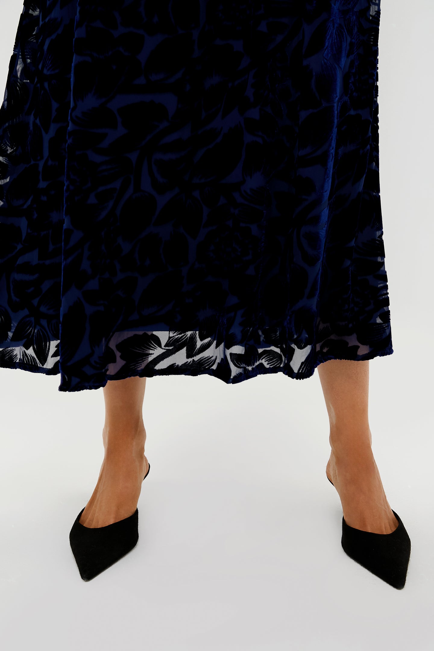 A person wearing a Hyacinth House navy floral dress and black pointed-toe heels stands against a light background.
