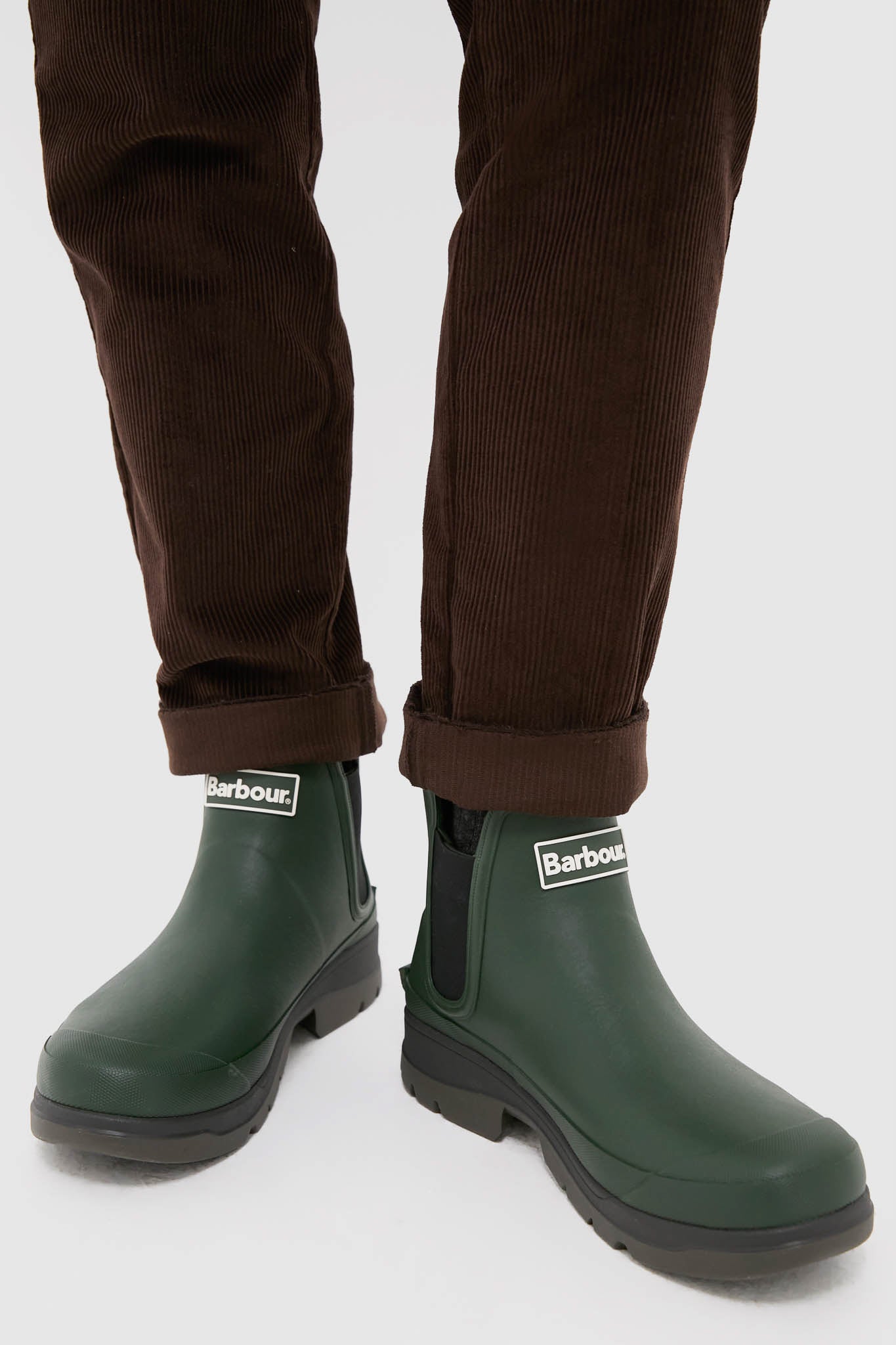 Olive Nimbus Chelsea Welly Boots showcase a classic, high-end design with elastic side panels and pull-tabs, effortlessly pairing with brown corduroys for a fun, stylish look.